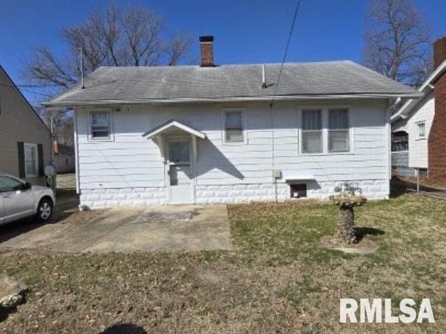 rear view of house with roof with shingles and a chimney