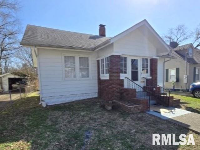 view of front facade with a front lawn, a chimney, and entry steps