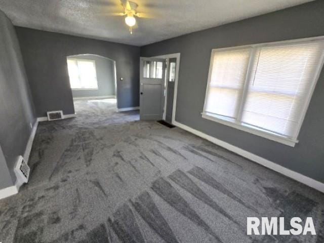 interior space with visible vents, ceiling fan, baseboards, carpet, and arched walkways