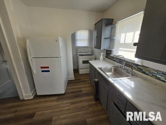 kitchen featuring a sink, dark wood-type flooring, light countertops, white appliances, and open shelves