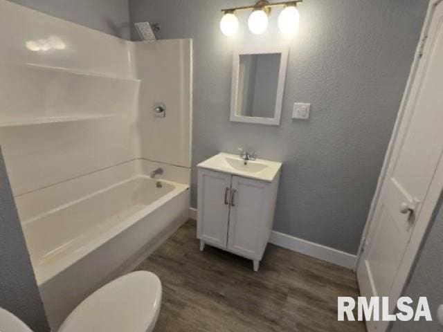 full bath featuring toilet, wood finished floors, shower / bathing tub combination, baseboards, and vanity