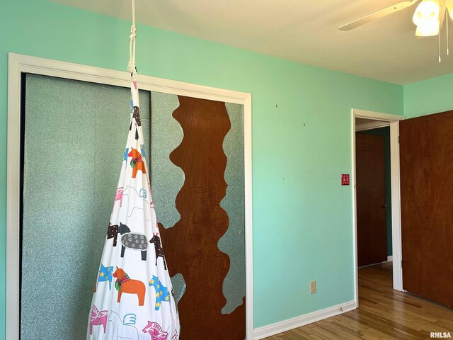 unfurnished bedroom featuring ceiling fan, baseboards, and wood finished floors