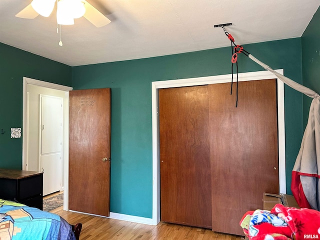 bedroom featuring ceiling fan, a closet, baseboards, and wood finished floors