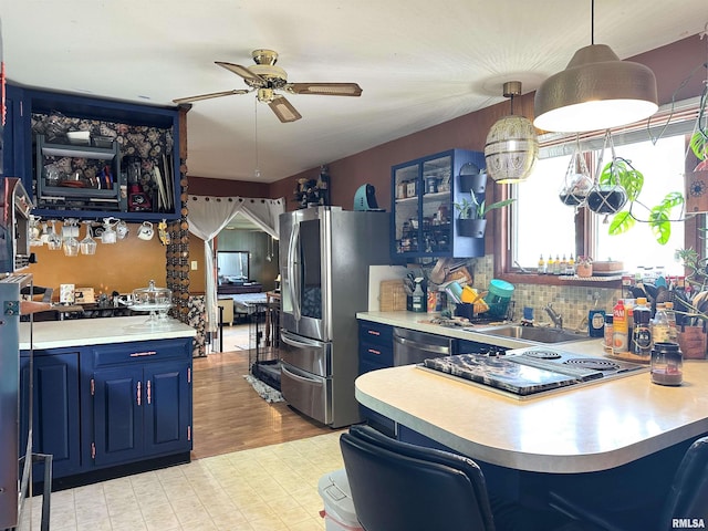 kitchen with a ceiling fan, blue cabinetry, a sink, light countertops, and appliances with stainless steel finishes