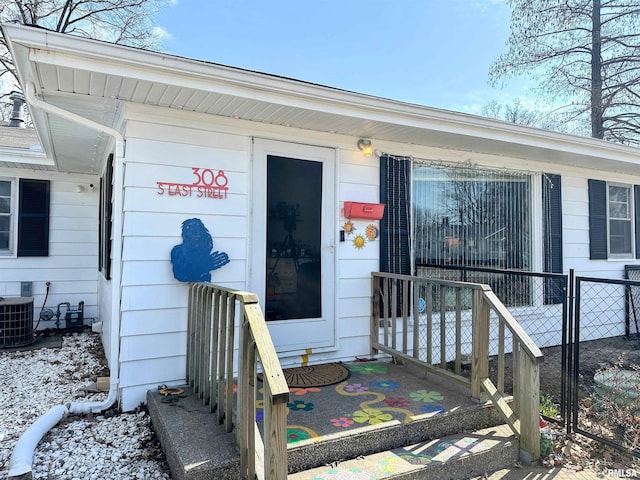 doorway to property featuring central AC unit and fence