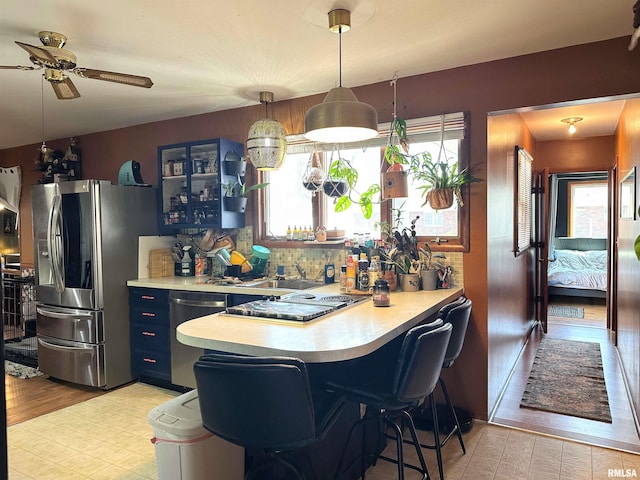 kitchen with tasteful backsplash, blue cabinetry, light countertops, appliances with stainless steel finishes, and a peninsula