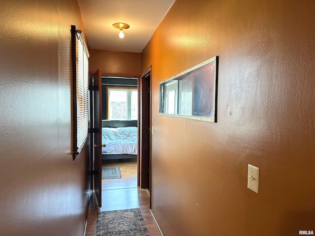 corridor with wood finished floors and a textured wall