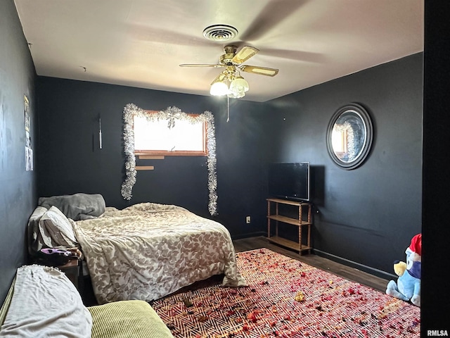 bedroom with a ceiling fan, wood finished floors, visible vents, and baseboards