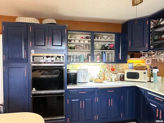 kitchen with blue cabinetry, white microwave, dobule oven black, and light countertops