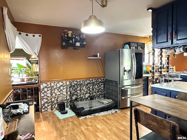 kitchen featuring light countertops, blue cabinetry, stainless steel fridge, and light wood-type flooring