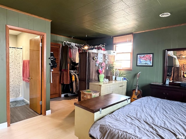 bedroom featuring ensuite bath, wood finished floors, and a closet