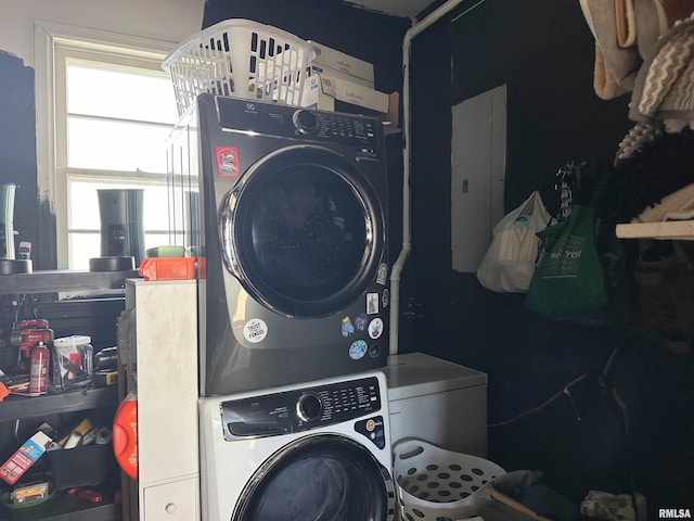 laundry room featuring electric panel, laundry area, and stacked washer and clothes dryer