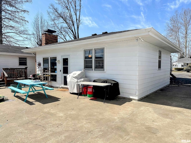 rear view of house featuring a patio area, a chimney, and a deck