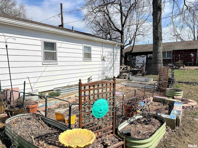 back of house with a vegetable garden and fence