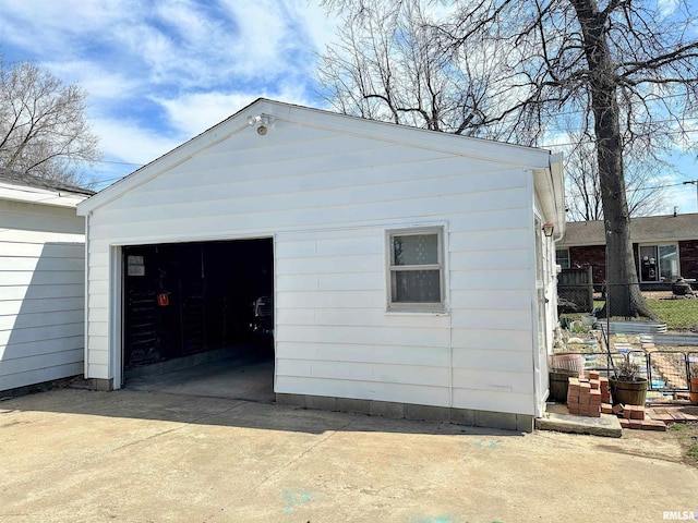 garage featuring driveway and fence