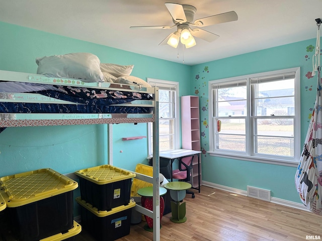 bedroom featuring ceiling fan, visible vents, baseboards, and wood finished floors