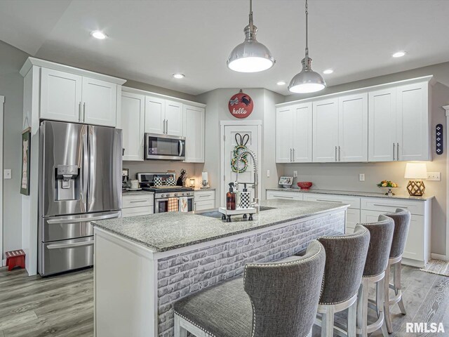 kitchen with a breakfast bar, light wood-type flooring, recessed lighting, stainless steel appliances, and white cabinetry