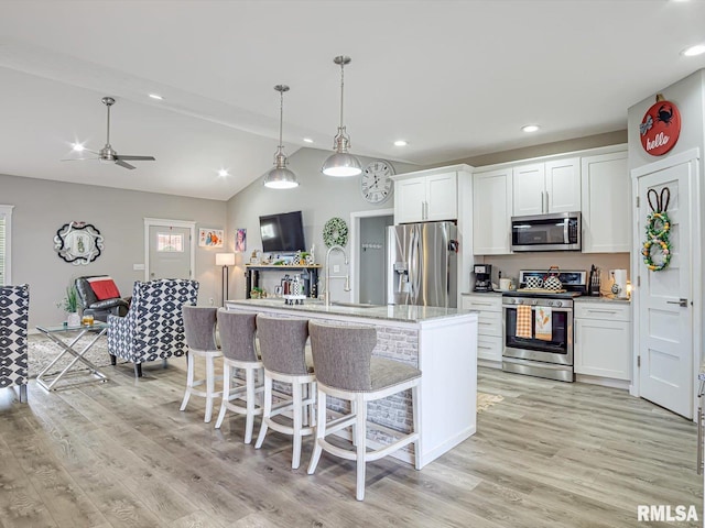 kitchen featuring a breakfast bar, white cabinets, stainless steel appliances, and light wood-type flooring