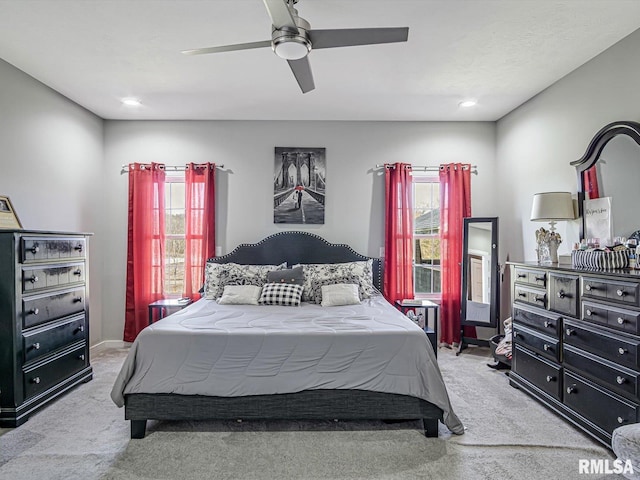 bedroom with a ceiling fan, multiple windows, and light colored carpet