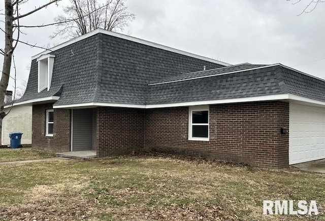 view of home's exterior with mansard roof, brick siding, and roof with shingles