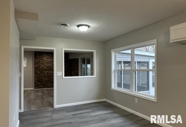 spare room with dark wood-type flooring, baseboards, and visible vents
