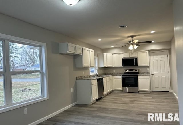 kitchen with a sink, white cabinets, baseboards, and stainless steel appliances