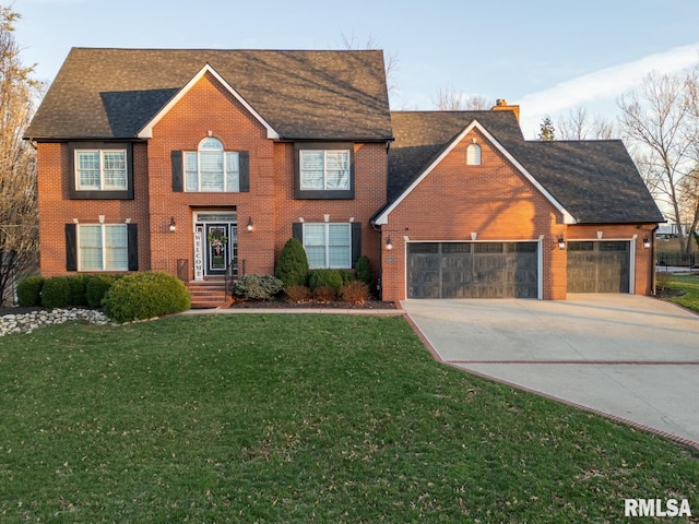 colonial-style house with driveway, an attached garage, a chimney, a front lawn, and brick siding