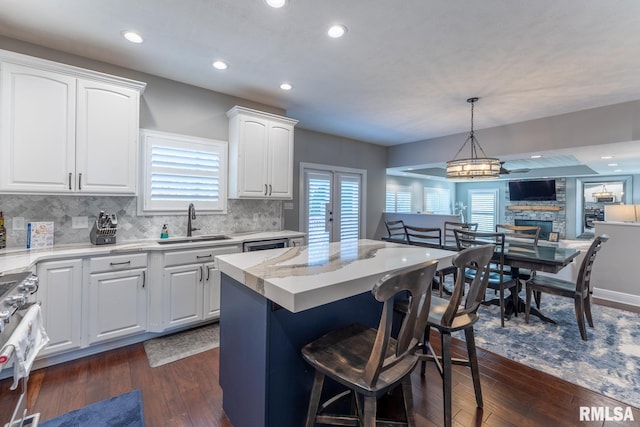 kitchen with dark wood-style floors, a kitchen breakfast bar, range, and a sink