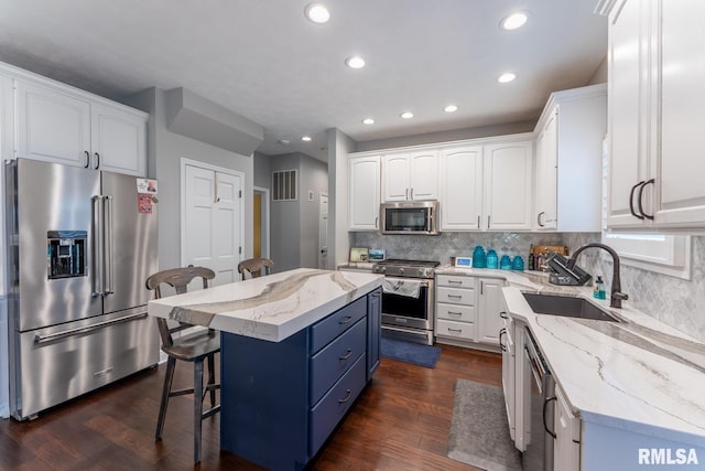 kitchen featuring a breakfast bar, white cabinetry, high quality appliances, and a sink