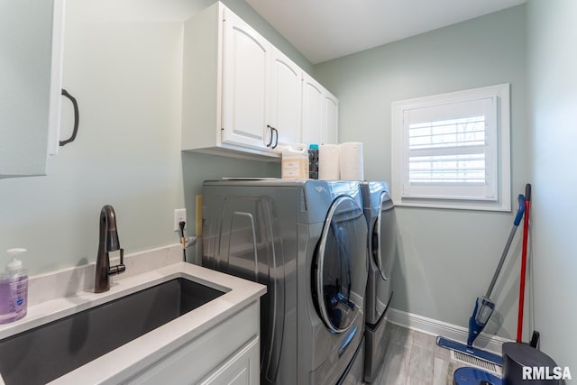 washroom featuring a sink, baseboards, wood finished floors, cabinet space, and separate washer and dryer