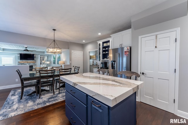kitchen with dark wood-type flooring, blue cabinets, high end fridge, and a kitchen island