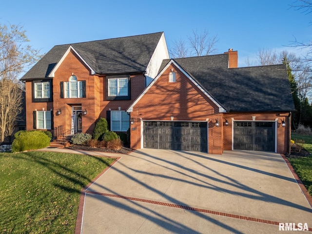 colonial home featuring brick siding, a front lawn, concrete driveway, a chimney, and an attached garage