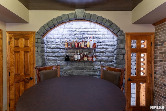 dining area featuring a dry bar and brick wall