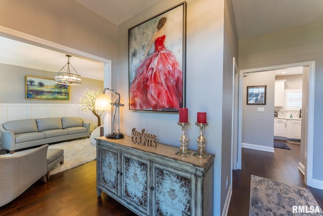 living room with dark wood finished floors, an inviting chandelier, and baseboards