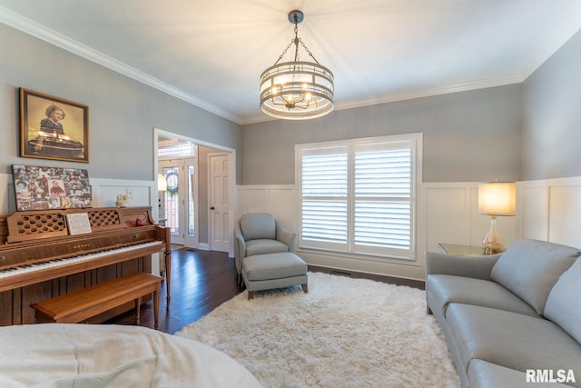 living area with crown molding, a notable chandelier, and wood finished floors