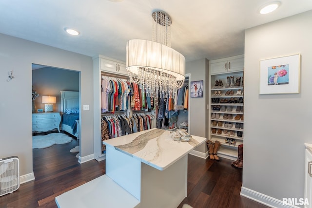 spacious closet featuring dark wood finished floors and an inviting chandelier