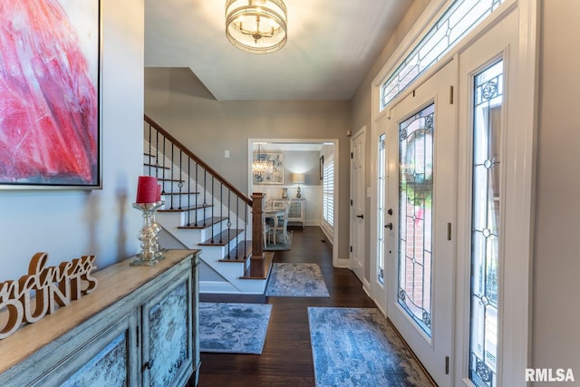 foyer entrance with baseboards, a notable chandelier, dark wood-style floors, and stairs
