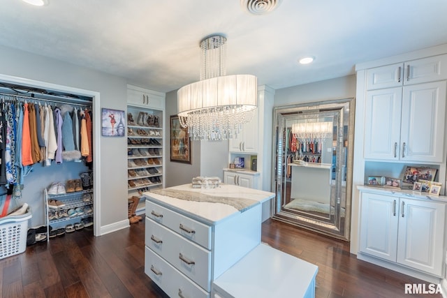 spacious closet featuring dark wood finished floors, a notable chandelier, and visible vents
