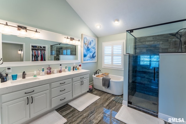 bathroom featuring a sink, wood finished floors, a shower stall, and vaulted ceiling
