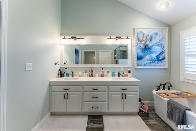 full bath with double vanity, a sink, a shower with shower door, and vaulted ceiling