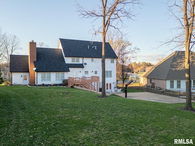 back of house with a lawn, a deck, a patio, stairway, and a chimney