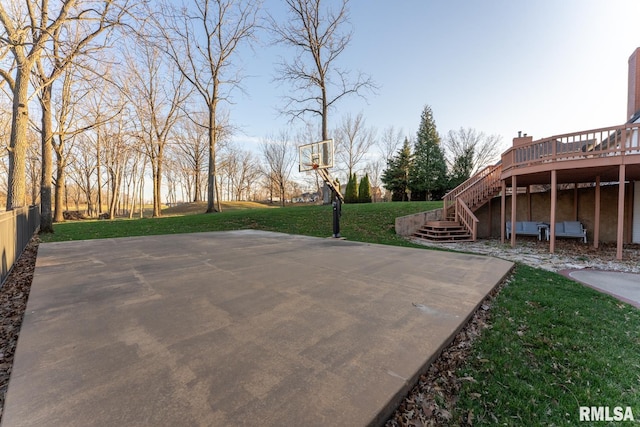 view of sport court with stairs, basketball hoop, and a yard