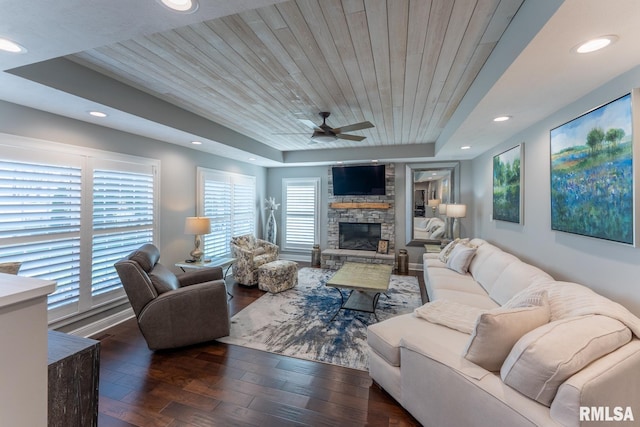 living room with ceiling fan, wood ceiling, a tray ceiling, and wood finished floors