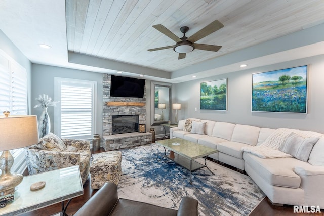living room with wood finished floors, a ceiling fan, a fireplace, wood ceiling, and a raised ceiling