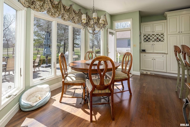 dining space with baseboards, an inviting chandelier, and dark wood finished floors