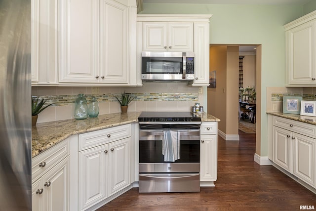 kitchen with dark wood-type flooring, baseboards, light stone counters, decorative backsplash, and stainless steel appliances
