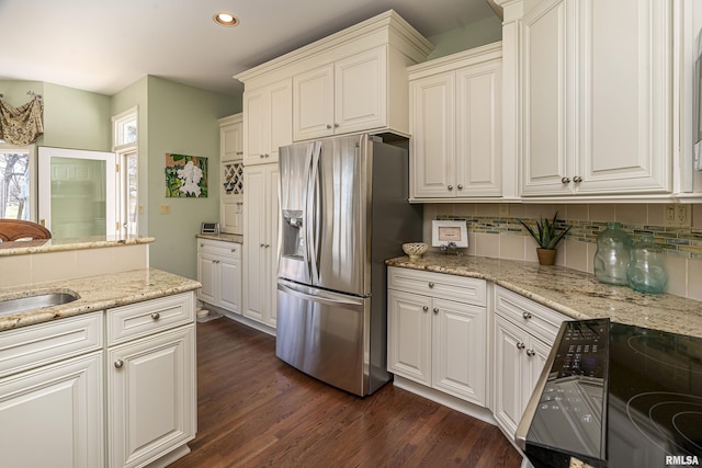 kitchen with stainless steel fridge with ice dispenser, light stone counters, decorative backsplash, range, and dark wood-style flooring