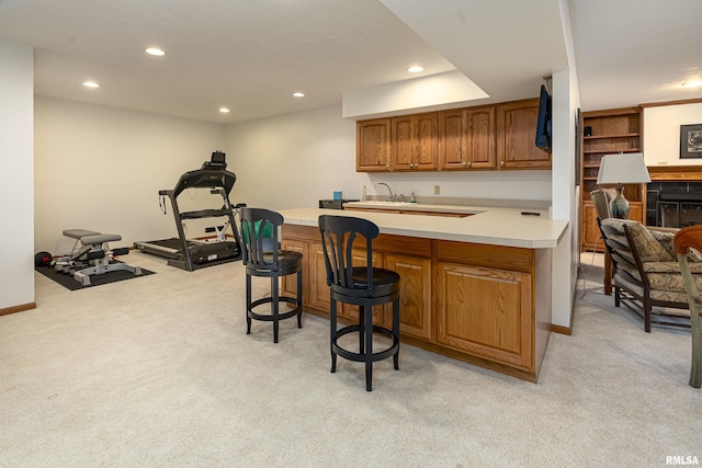 kitchen with a kitchen breakfast bar, recessed lighting, a peninsula, brown cabinetry, and light colored carpet