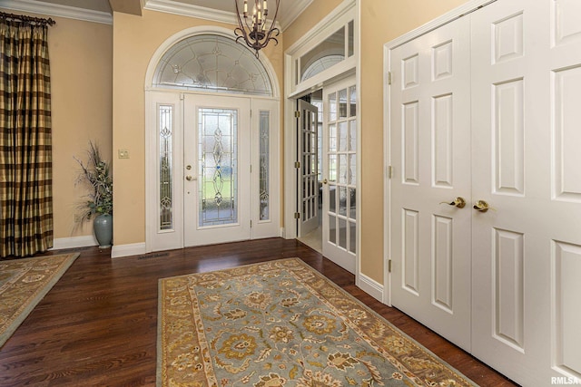 entrance foyer featuring crown molding, baseboards, dark wood-style flooring, and a chandelier