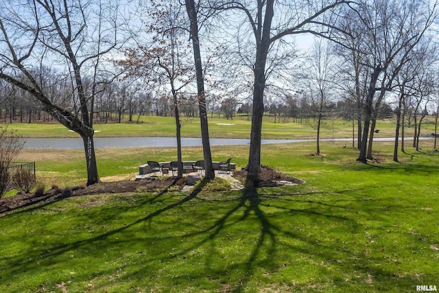 view of property's community with a water view, a lawn, and an outdoor fire pit